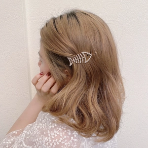 Cute fish bone hair clip with white crystals on a gold base worn by a model