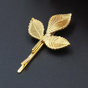 Eleganter goldener Blatt-Haarclip für Damen mit dreilagigem Laub auf dunklem Hintergrund