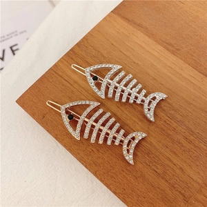 Cute fish bone hair clips in gold and silver set with sparkling rhinestones on wood