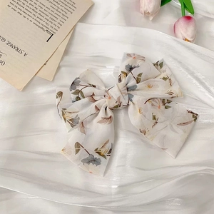 Détail d'une barrette à nœud en mousseline fleurie sur un tissu en satin blanc élégant