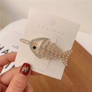 Macro detail of a gold fishbone hair clip with white rhinestones on display card