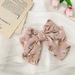 Gros plan d'une pince à cheveux à nœud floral rose en mousseline sur du satin