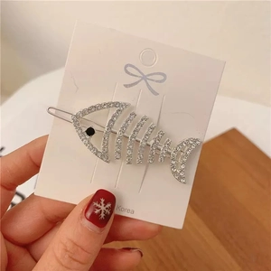 Detailed view of a silver fishbone hair clip with sparkling rhinestones and black eye