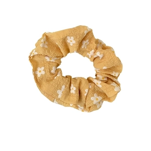 Floral yellow scrunchie with white daisy pattern made of textured cotton fabric