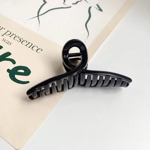 Gros plan d'une grande pince à cheveux noire brillante au design croisé élégant