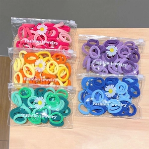 50-piece colorful hair tie set with daisy packaging on a minimalist wooden table