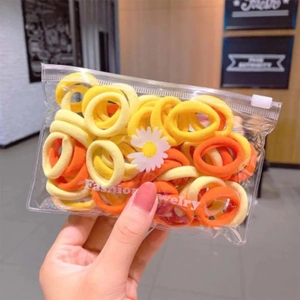 Detail of yellow and orange elastic hair ties in a daisy zip pouch for girls