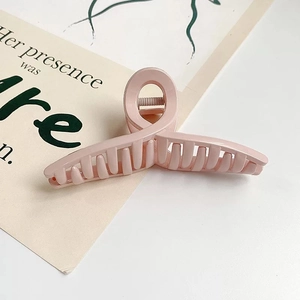 Détail d'une grande pince à cheveux rose mat avec un design de nœud torsadé moderne