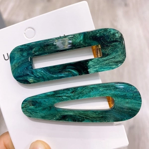 Detailed macro of dark green marble emerald acetate hair clips with golden glitter finish
