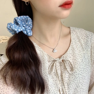 Chouchou bleu fleuri et collier pendentif papillon argenté sur un mannequin