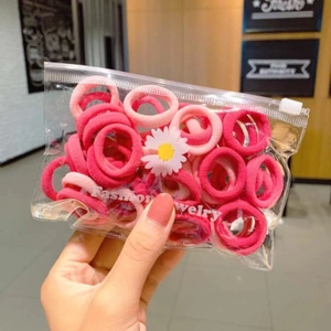 Close-up of pink elastic hair ties in a clear zipper bag with daisy sticker and jewelry text