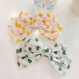 Dual pack of white satin bow hair clips with orange and green heart patterns for women