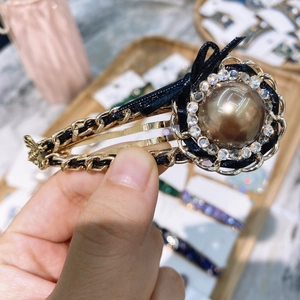 Retro hair clip featuring a large brown pearl, crystal halo and black leather chain