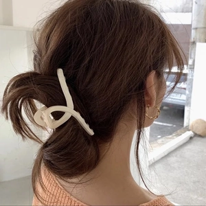 Pince à cheveux croisée beige mat et boucles d'oreilles créoles dorées sur le modèle