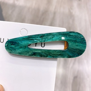 Detail of emerald green acetate hair clip with marble texture and gold foil accents