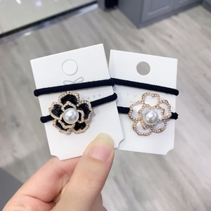 Detailed view of camellia hair ties featuring pearl embellishments and golden edges