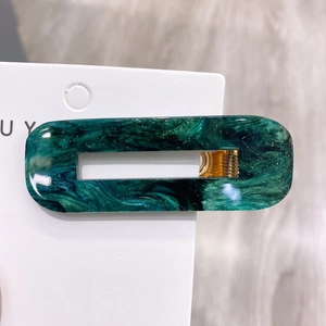 Close-up of emerald green marble acetate hair clip with gold glitter and metal clip detail