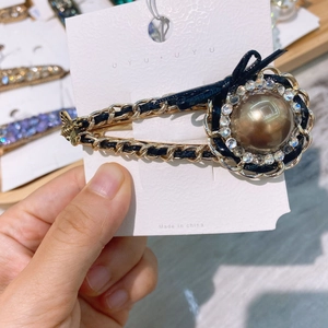 Close-up of vintage hair clip featuring a faux pearl center and woven metal chain detail