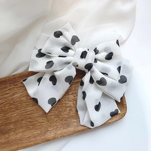 Detailed macro view of a layered white chiffon hair bow with black heart patterns