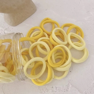Gros plan d'élastiques à cheveux tricotés en jaune et beige sur une surface en pierre