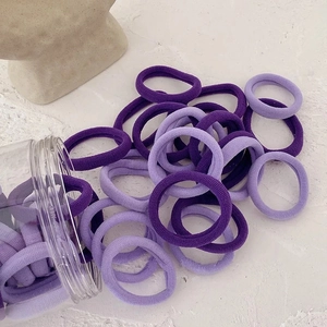 Gros plan d'élastiques à cheveux violets sans couture dans un bocal sur fond de pierre