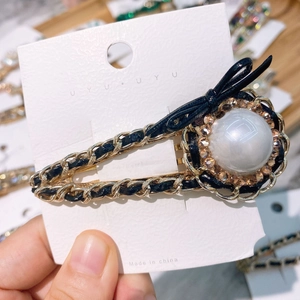 Detail of vintage hairpin featuring gold chain, large pearl, and black bow decoration