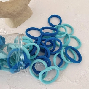 Élastiques à cheveux bleus sans couture sortant d'un pot de rangement transparent