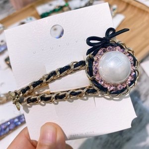 Detailed macro shot of vintage woven chain hair clip with pink rhinestones and pearl
