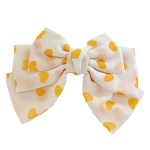 Oversized white satin hair bow with yellow heart pattern and layered ribbon design