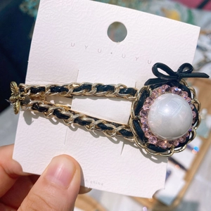 Detail of vintage bow hair clip with pearls and chain, hand-held macro view