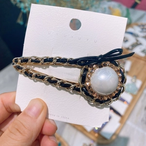Detail of luxury hair clip featuring a large white pearl and champagne crystal accents