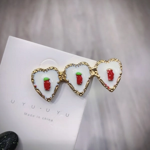 Dettaglio di fermaglio per capelli a cuore con smalto bianco e decorazioni a fragola
