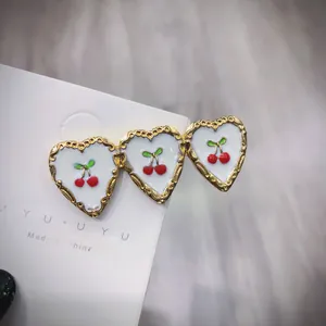 Dettaglio di tre fermagli per capelli a cuore bianco con ciliegie e bordi dorati