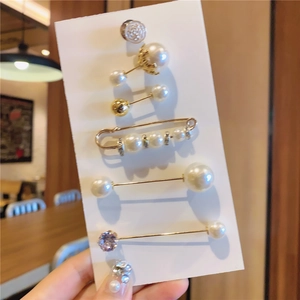 Détail d'un lot de six broches décoratives avec perles et cristaux sur une carte