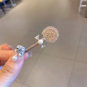 Détail de la pince à cheveux sucette avec strass et nœud en perles, finition or rose
