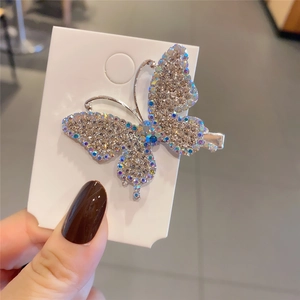 Detailed view of a silver butterfly hair clip encrusted with colorful iridescent rhinestones
