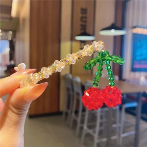 Detailed view of handmade beaded cherry hair clip with sparkling yellow crystal accents