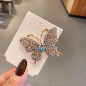 Close-up of butterfly hair clip with colorful rhinestones on a golden metal base