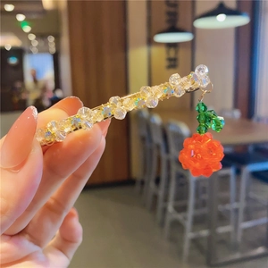 Close-up of handmade beaded hair clip with crystal beads and red rose charm on gold metal