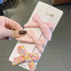 Dettaglio ravvicinato di un set di tre fermagli per capelli con fiocchi rosa su cartoncino