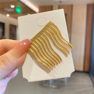 Macro detail of wave texture on a gold metal hair comb slide for vintage styling
