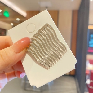 Detail of silver wavy metal hair comb teeth on display card held by a hand