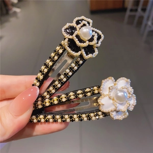 Dettaglio di fermagli per capelli a camelia con grandi perle bianche e strass neri