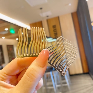 Detail of wave-shaped hair comb in gold and silver finish with metallic shine