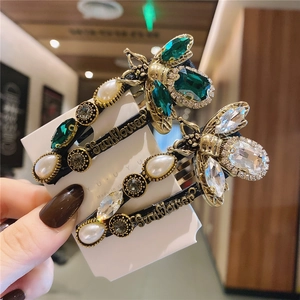 Detail view of vintage bee hair clip with green crystals, pearls and Sunflower engraving