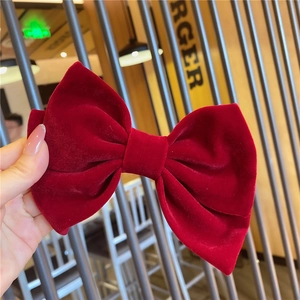 Detailed view of a large burgundy velvet bow hair clip with a soft matte texture