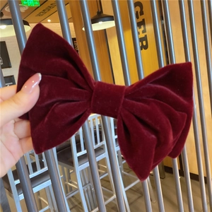 Detail of large burgundy velvet bow hair clip with French vintage pleats texture