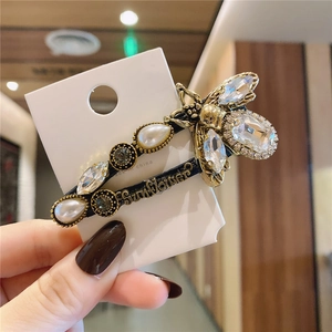 Detail view of a vintage bee hair clip with white pearls and sparkling crystals