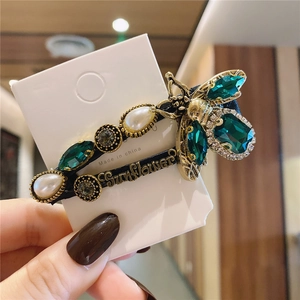 Detail of vintage emerald crystal hair clip with honeybee and sunflower engraving
