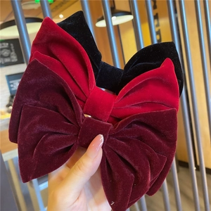 Detail showing oversized velvet bow hair clips in wine red, bright red and black colors